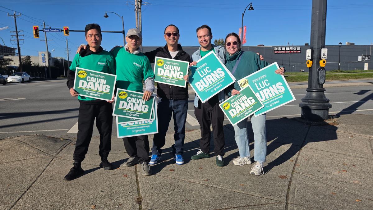 BC Greens supports with candidate Calvin Dang and Luc Burns waving sign on a road crossing in Richmond, BC.